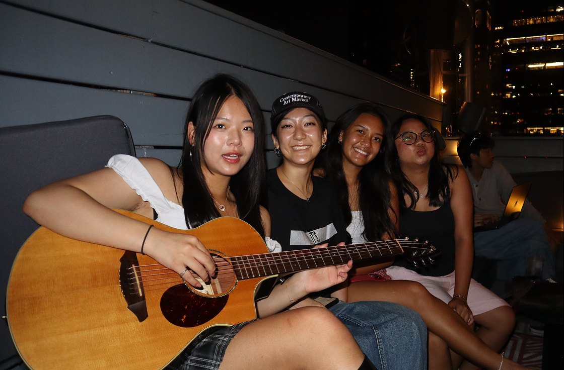 Friends on a rooftop at night, Jean with a guitar