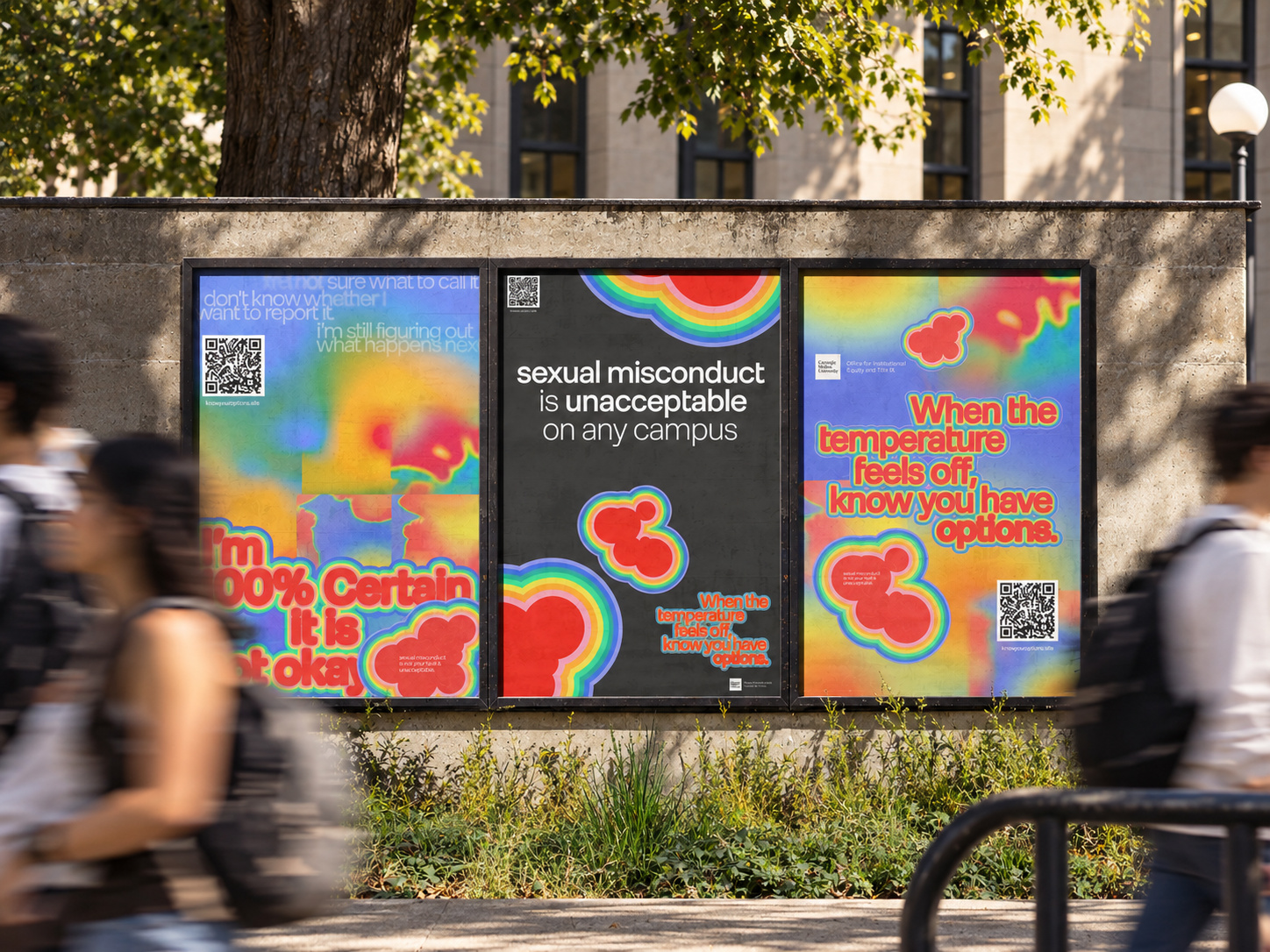 Three campaign posters on an outdoor wall on campus as students walk past